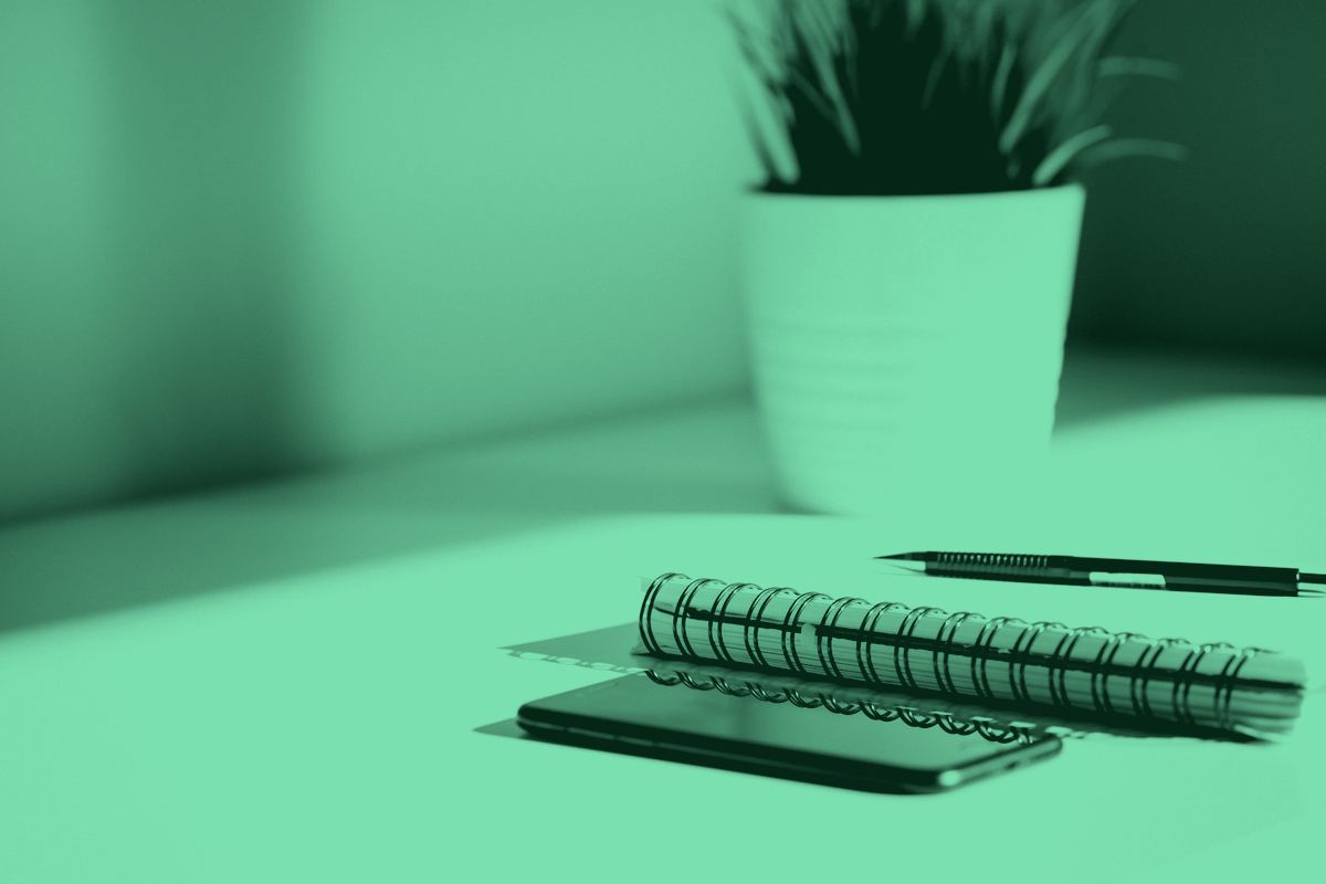 A phone and a notebook on a white desk